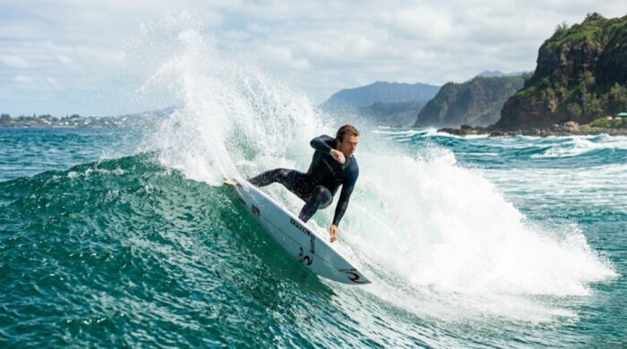 An experienced surfer carving a powerful wave on a shortboard surfboard.