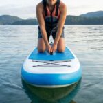 Beginner balancing on a Niphean paddle board in calm water