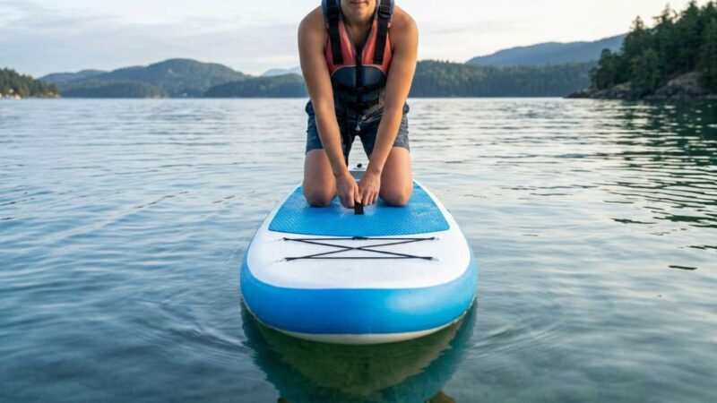 Beginner balancing on a Niphean paddle board in calm water