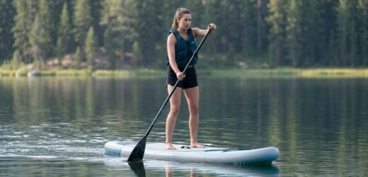 Beginner steering a Niphean inflatable paddle board on calm water